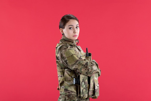 Vue de face femme soldat en uniforme militaire sur mur rouge