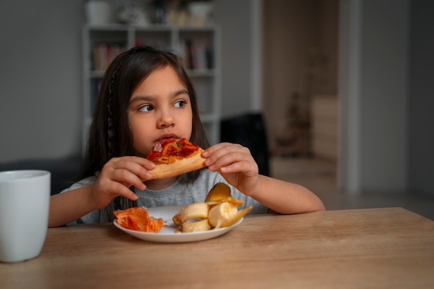 Photo vue de face fille mangeant de la pizza à la maison