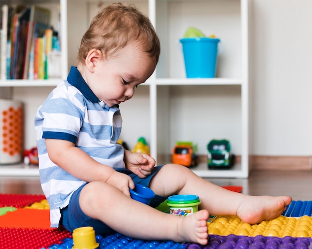 Vue de face de l'heureux petit garçon mignon jouant avec des jouets