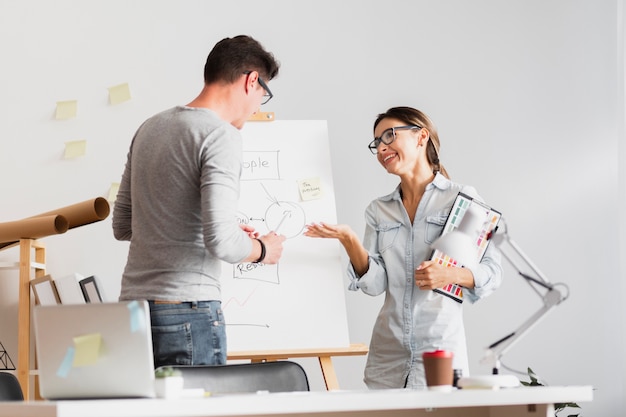 Vue de face homme et femme parlant d'un schéma d'entreprise