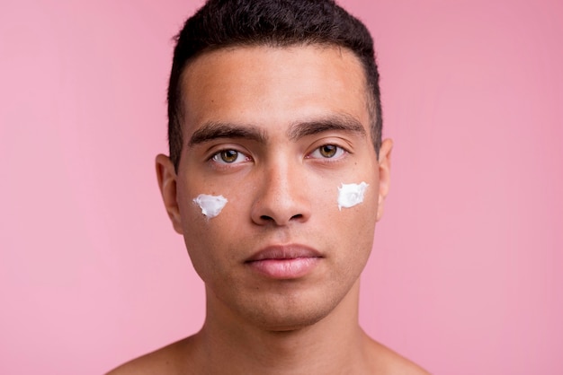 Photo vue de face de l'homme posant avec de la crème pour le visage sur