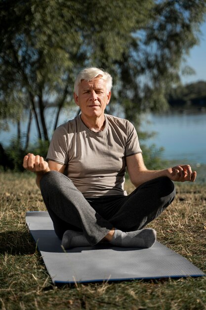 Vue de face de l'homme pratiquant le yoga à l'extérieur