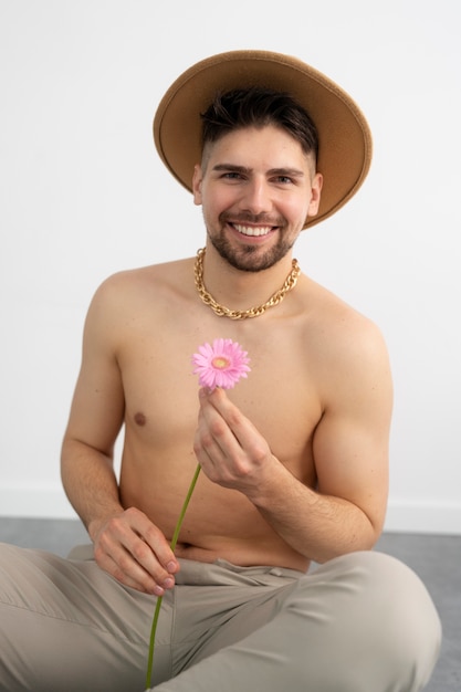Vue de face homme souriant posant avec une fleur