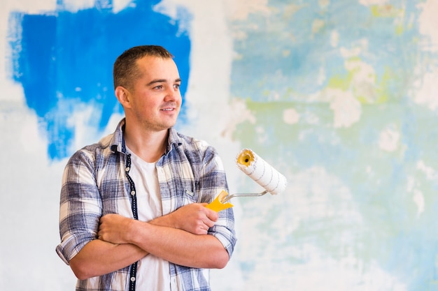 Photo vue de face d'un homme tenant un rouleau à peinture