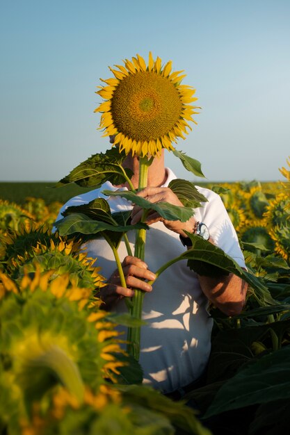 Photo vue de face homme tenant tournesol