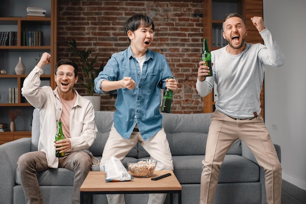 Vue de face d'hommes regardant un match de football à la télévision et buvant une bière