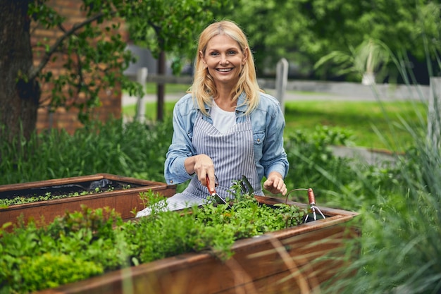 Vue de face d'une horticultrice heureuse avec une truelle à la main posant pour la caméra