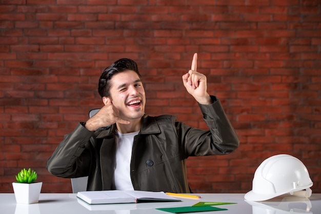 Vue de face ingénieur masculin assis derrière son lieu de travail emploi entrepreneur ordre du jour constructeur document propriété entreprise entreprise