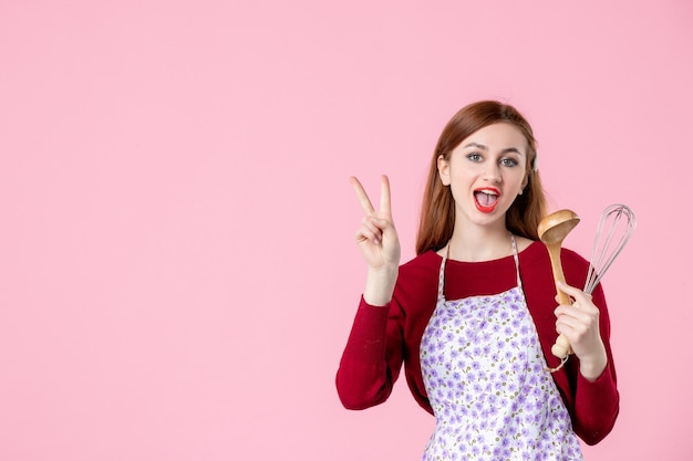 Vue de face jeune femme au foyer avec cuillère et fouet sur fond rose couleur cuisine cuisine cuisine pâte sucrée nourriture femme gâteau tarte