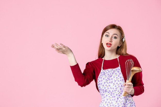 vue de face jeune femme au foyer avec cuillère et fouet sur fond rose couleur douce cuisine cuisine femme gâteau tartes pâte cuisine