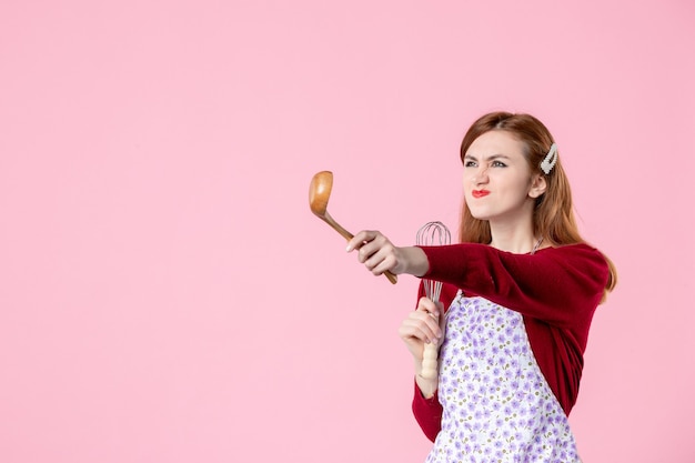 vue de face jeune femme au foyer avec cuillère et fouet sur fond rose couleur douce cuisine femme nourriture gâteau cuisine pâte cuisson