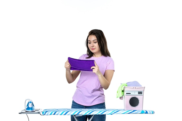Vue de face jeune femme au foyer se prépare à repasser une serviette violette sur fond blanc travaux ménagers couleur travail propre femme blanchisserie émotion