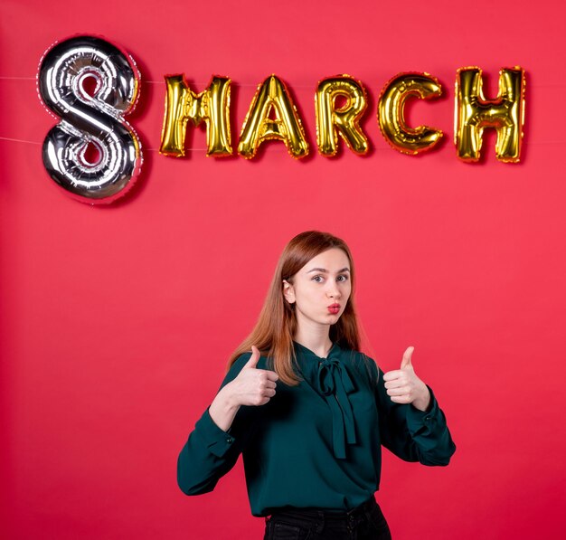 Vue de face jeune femme en chemisier vert avec décoration de mars sur fond rouge couleur vacances monde cadeau cadeau femme d'amour