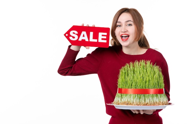 Vue de face jeune femme holding big novruz semeni et vente plaque signalétique sur fond blanc couleurs de printemps origine ethnique shopping famille interprète ethnique