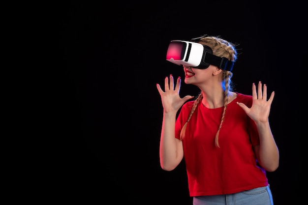 Vue de face d'une jeune femme jouant au vr sur un mur sombre