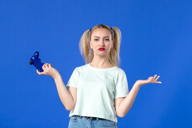 vue de face jeune femme jouant à un jeu vidéo avec manette de jeu sur fond bleu joueur de canapé virtuel adulte jeunesse en ligne joyeuse vidéo gagnante