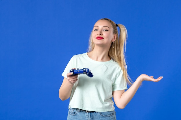 vue de face jeune femme jouant à un jeu vidéo avec manette de jeu sur fond bleu joystick jeunesse adulte joueur gagnant en ligne virtuel