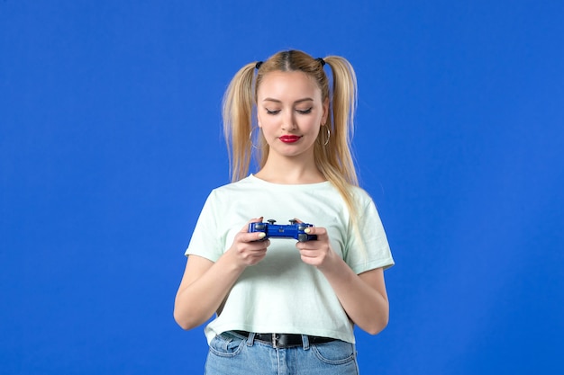 vue de face jeune femme jouant à un jeu vidéo avec manette de jeu sur fond bleu joystick virtuel gagnant joyeuse vidéo de joueur de jeunesse adulte