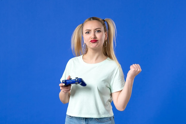 vue de face jeune femme jouant à un jeu vidéo avec manette de jeu sur fond bleu joystick virtuel gagnant en ligne vidéo jeunesse adulte joueur joyeux