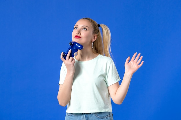 vue de face jeune femme avec manette de jeu sur fond bleu joueur de joie virtuelle en ligne jeunesse joystick vidéo joystick adulte