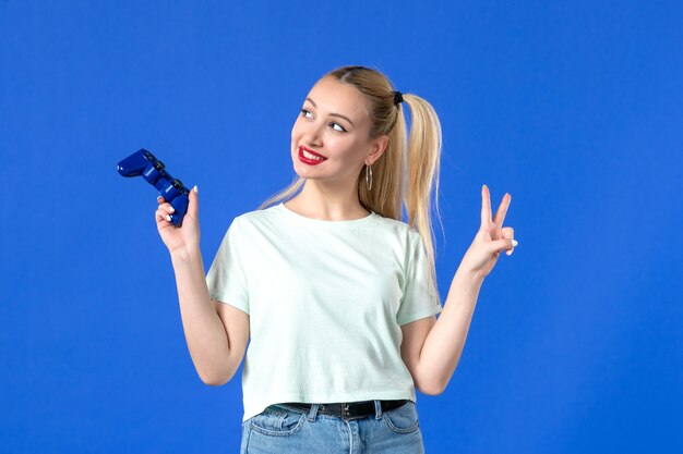 vue de face jeune femme avec manette de jeu sur fond bleu vidéo joueur de joie virtuelle jeunesse joyeuse manette gagnante adultes en ligne