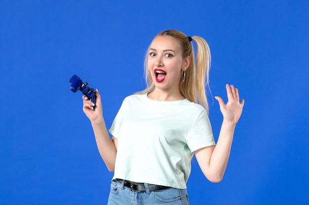 vue de face jeune femme avec manette de jeu sur fond bleu vidéo joueur de joie virtuelle jeunesse joyeux gagnant adulte en ligne