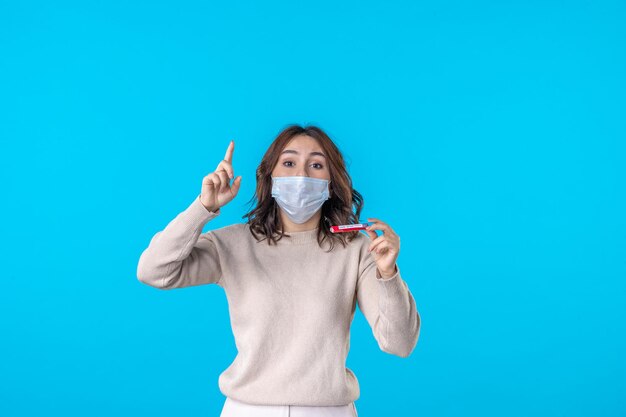 vue de face jeune femme en masque avec flacon sur fond bleu science virus médical covid maladie pandémique santé isolement