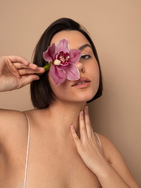 Photo vue de face jeune femme posant avec une fleur