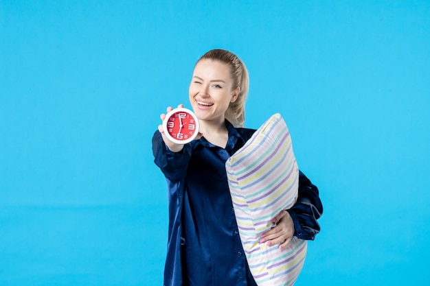 vue de face jeune femme en pyjama avec horloge et oreiller sur fond bleu nuit fête reste cauchemar sommeil fatigué fin rêve lit