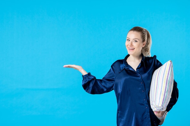 Vue de face jeune femme en pyjama tenant un oreiller sur fond bleu soirée cauchemar femme lit couleur rêve bâillement repos nocturne