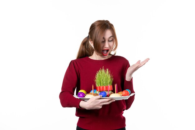 Vue de face d'une jeune femme tenant honca avec des bonbons semeni et novruz sur fond blanc couleurs de vacances concept ethnique interprète de printemps ethnique