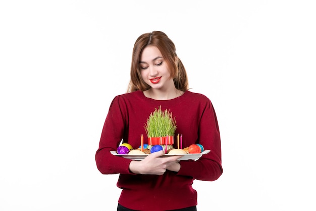 Vue de face de jeune femme tenant honca avec bonbons semeni et novruz sur fond blanc vacances ethnicité interprète couleurs concept printemps