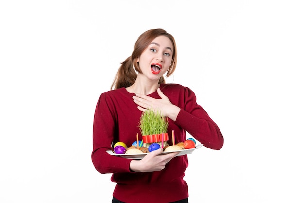 Vue de face d'une jeune femme tenant honca avec des bonbons semeni et novruz sur fond blanc vacances ethniques couleurs interprète printemps ethnique