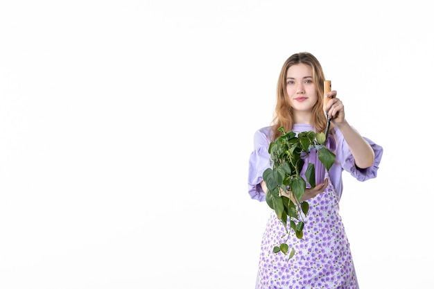 Vue de face jeune femme tenant une spatule et une fleur sur fond blanc fleur herbe plante femme shopping sol sol