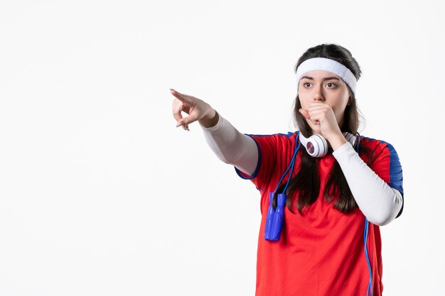 Vue de face jeune femme en vêtements de sport avec des cordes à sauter sur un mur blanc