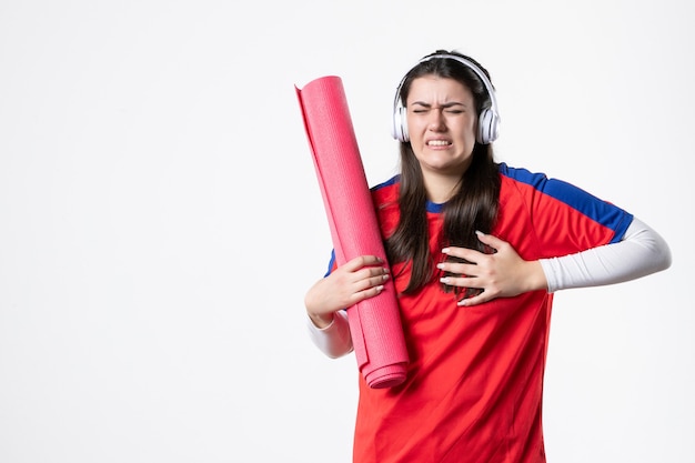 Vue de face jeune femme en vêtements de sport tenant un tapis de yoga