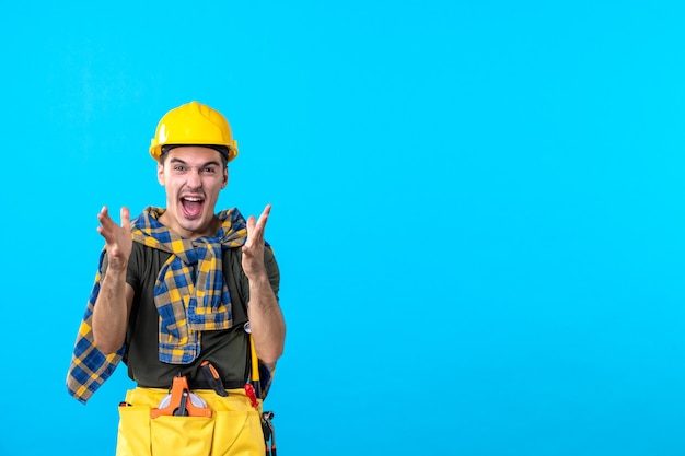 Vue de face jeune homme builder en casque jaune sur fond bleu architecture constructeur travailleur couleur plate construction d'outils