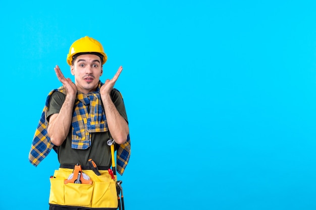 Vue de face jeune homme builder en casque jaune sur fond bleu constructeur d'outils de travail architecture bâtiment couleurs plates