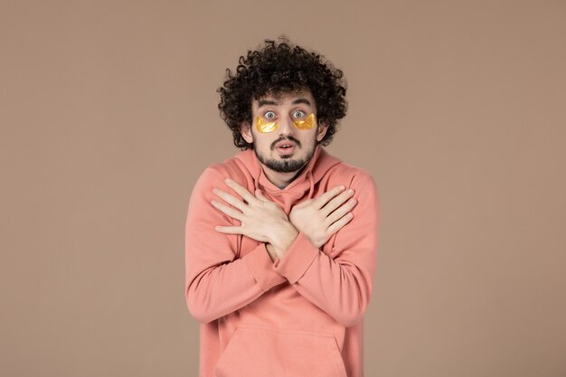 vue de face jeune homme avec cache-œil sur fond marron massage de la peau spa crème de soin horizontale