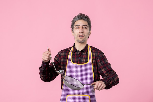 vue de face jeune homme en cape avec tamis et cuillère sur fond rose uniforme travailleur nourriture mari cuisine horizontale cuisine soupe profession