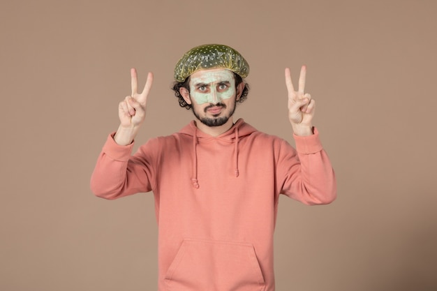 vue de face jeune homme avec casquette bouffante sur fond marron salon thérapie de la peau cheveux massage du visage spa