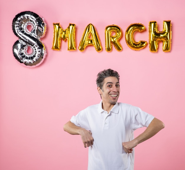 Photo vue de face jeune homme avec décoration de mars sur fond rose égalité émotion fête des femmes fête couleur sensuelle