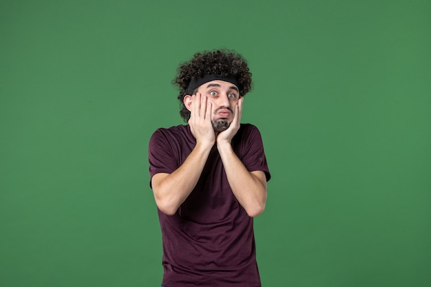 Vue de face jeune homme sur fond vert couleur sport gym entraînement athlète exécutant l'émotion du modèle de mode de vie de la santé