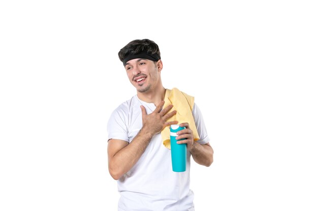 Vue de face jeune homme holding thermos après séance d'entraînement sur fond blanc sport lifestyle corps régime athlète yoga gym fit