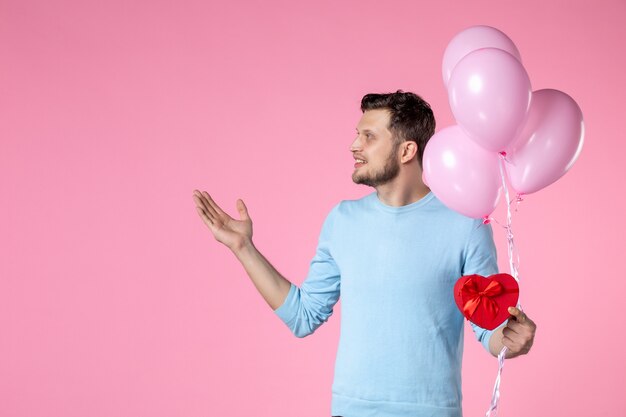 vue de face jeune homme avec de jolis ballons roses et cadeau en forme de coeur sur fond rose fête des femmes mariage mars sensuel féminin amusement amour parc date