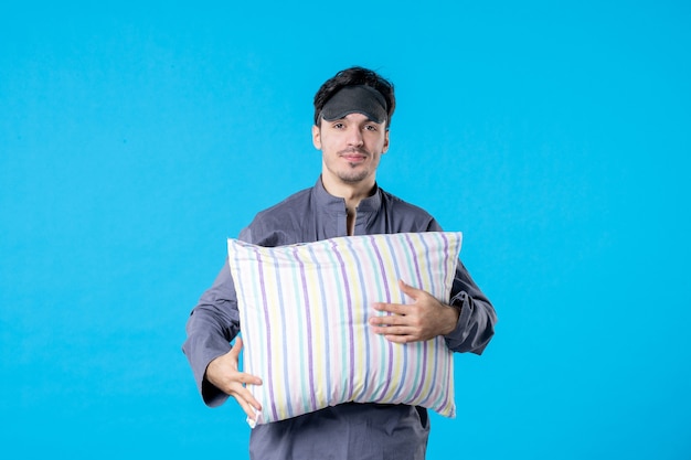 vue de face jeune homme en pyjama et bandage pour dormir tenant un oreiller sur fond bleu nuit couleur fin repos humain réveil sommeil lit de rêve