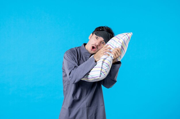 vue de face jeune homme en pyjama essayant de dormir sur un oreiller sur fond bleu couleur de nuit fin cauchemar réveil humain sommeil rêve repos lit