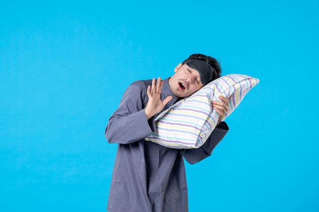 Vue de face jeune homme en pyjama essayant de dormir sur un oreiller sur fond bleu nuit de sommeil couleur fin de réveil humain lit reste cauchemar