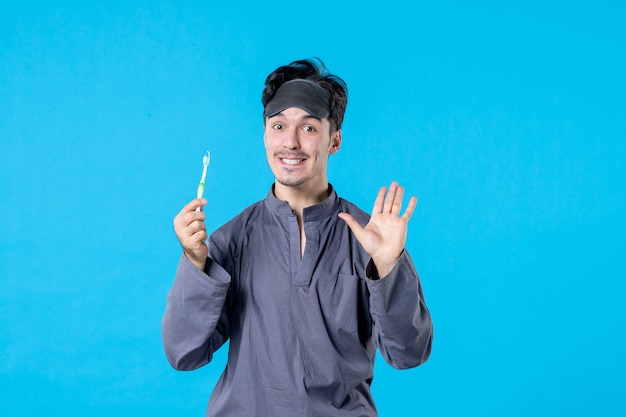 vue de face jeune homme en pyjama montrant ses dents propres sur fond bleu rêve cauchemar repos nocturne réveil propre lit humain