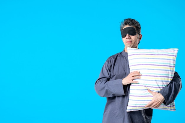 vue de face jeune homme en pyjama avec oreiller sur fond bleu couleur de rêve nuit cauchemar lit sommeil repos chambre